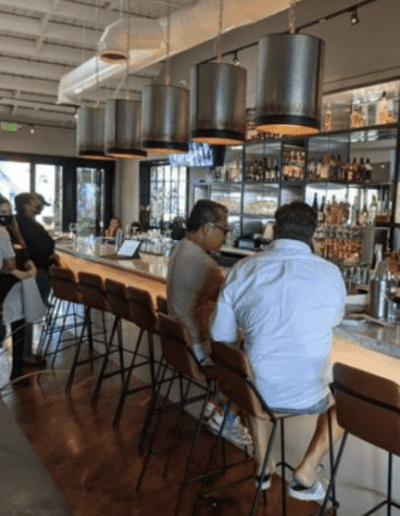 A group of people sitting at a bar in a restaurant.